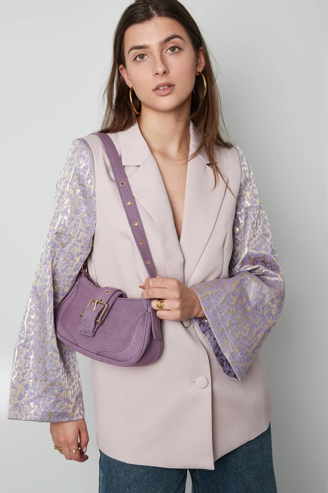 Mujer con bolso morado minimalista y chaqueta elegante, estilo atemporal y sofisticado