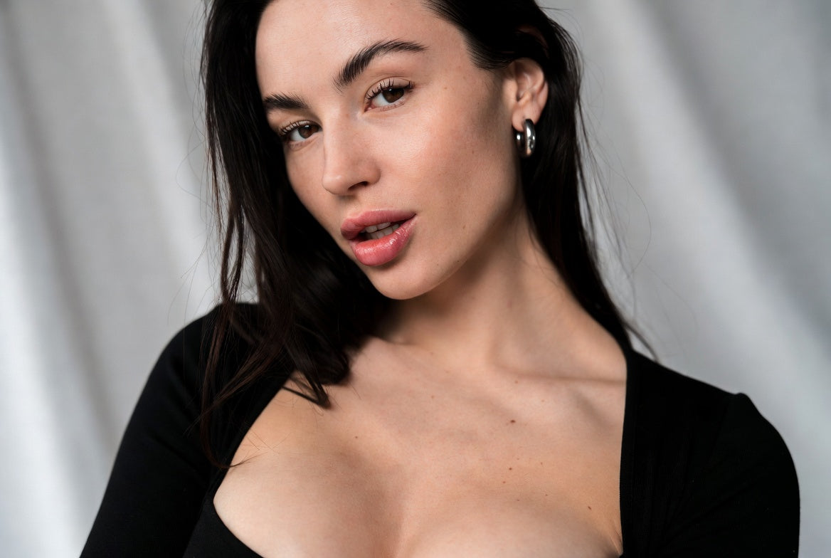 Mujer con blusa negra minimalista y pendientes, estilo atemporal
