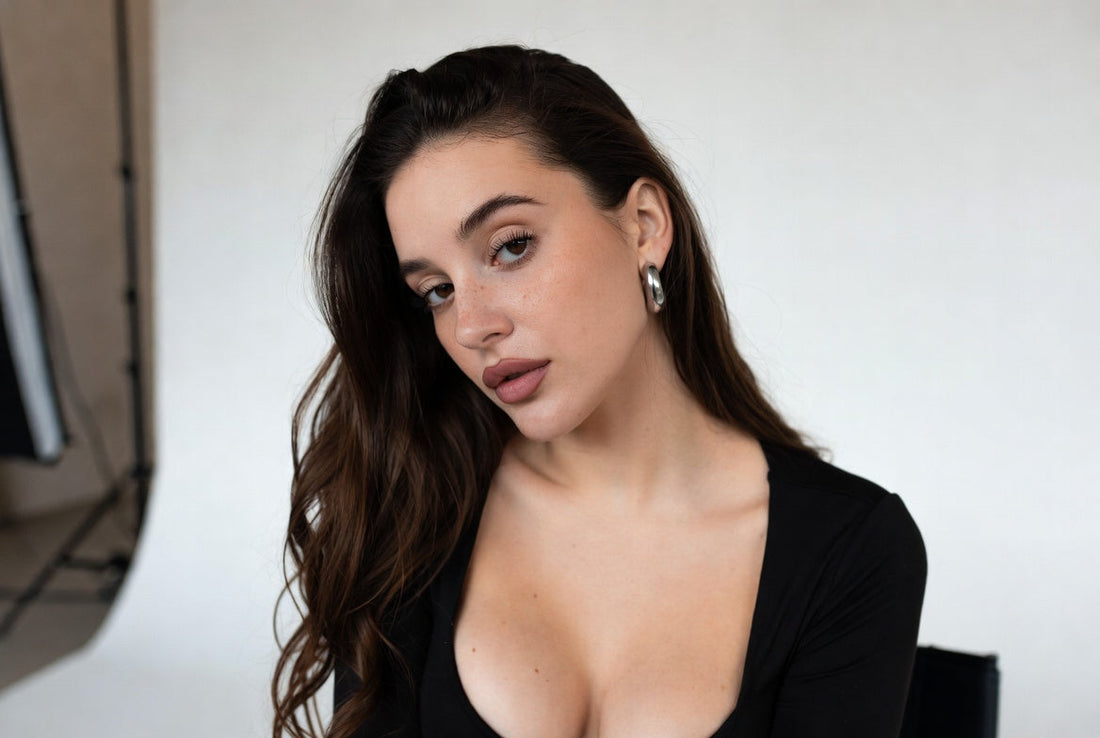 Mujer con cabello ondulado y blusa negra en estudio minimalista, estilo atemporal y sin esfuerzo