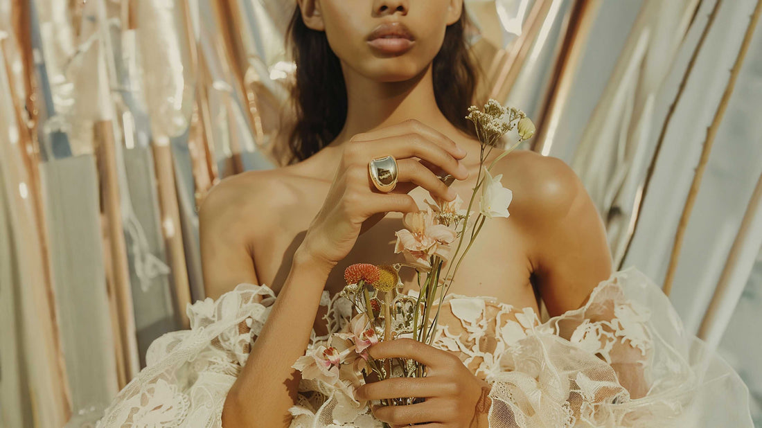 Mujer con vestido de encaje, flores secas y anillo dorado
