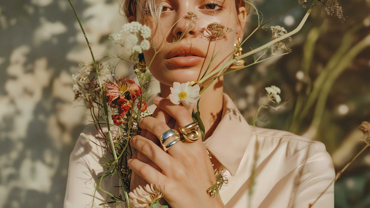 Mujer con anillos minimalistas y flores silvestres, estilo natural
