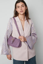 Mujer con bolso morado minimalista y chaqueta elegante, estilo atemporal y sofisticado